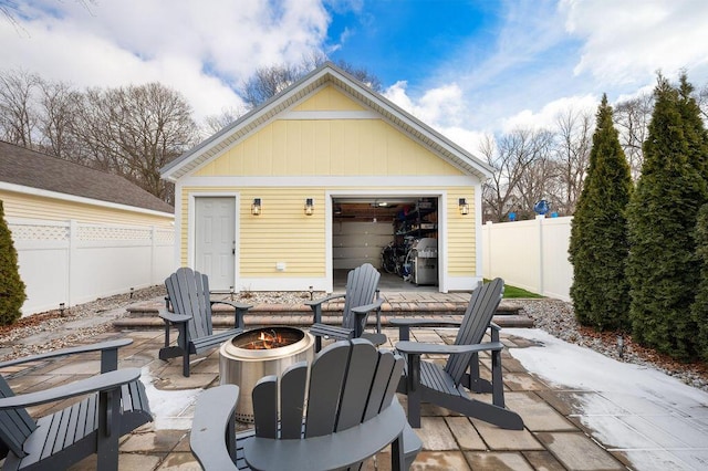 view of patio featuring a fire pit, an outdoor structure, and fence private yard