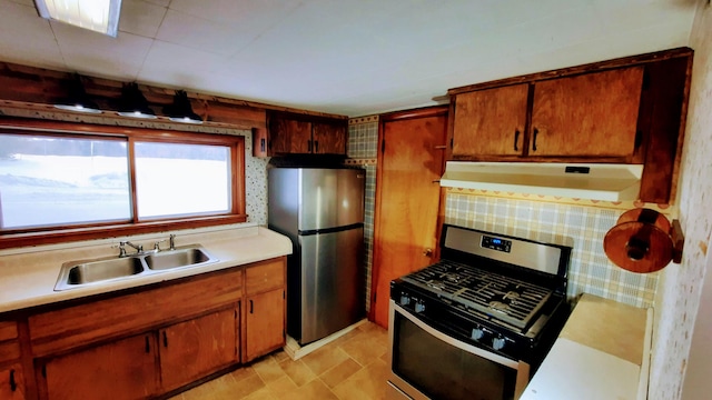 kitchen featuring brown cabinets, light countertops, appliances with stainless steel finishes, a sink, and ventilation hood