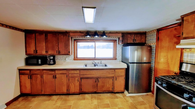 kitchen with brown cabinetry, stainless steel appliances, light countertops, under cabinet range hood, and a sink