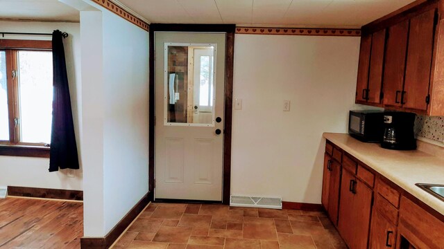 kitchen featuring black microwave, light countertops, visible vents, and baseboards