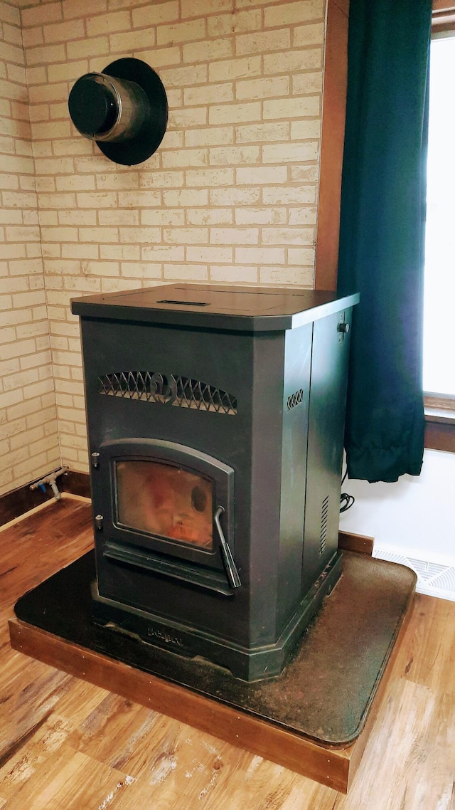 details featuring a wood stove, visible vents, and wood finished floors