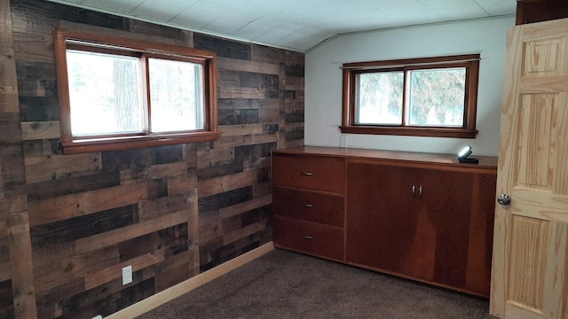 interior space featuring lofted ceiling, carpet, and wooden walls