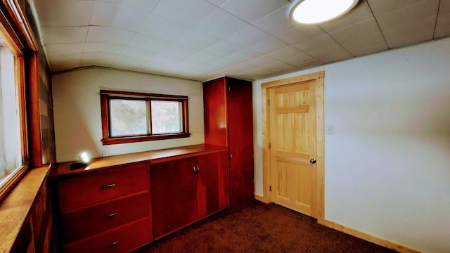 hall with dark carpet and baseboards