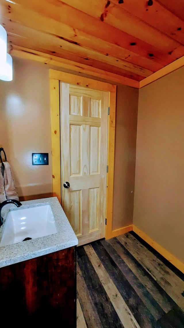 bathroom featuring wooden ceiling, vanity, baseboards, and wood finished floors