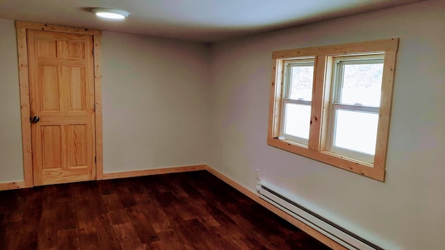 spare room with baseboard heating, dark wood finished floors, and baseboards