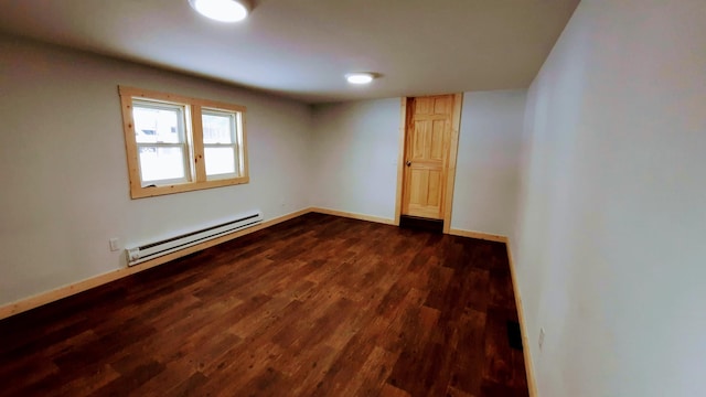 empty room featuring dark wood-type flooring, a baseboard radiator, and baseboards