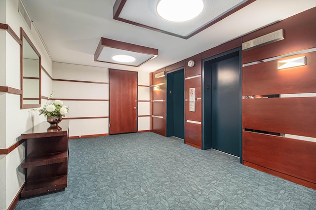 corridor featuring carpet floors, elevator, baseboards, and visible vents