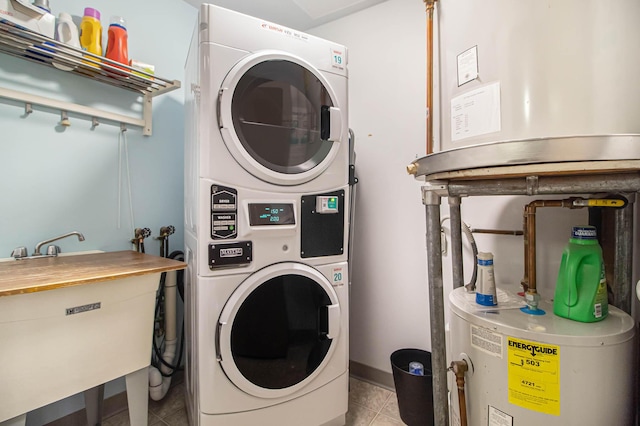 washroom with light tile patterned floors, laundry area, a sink, water heater, and stacked washing maching and dryer