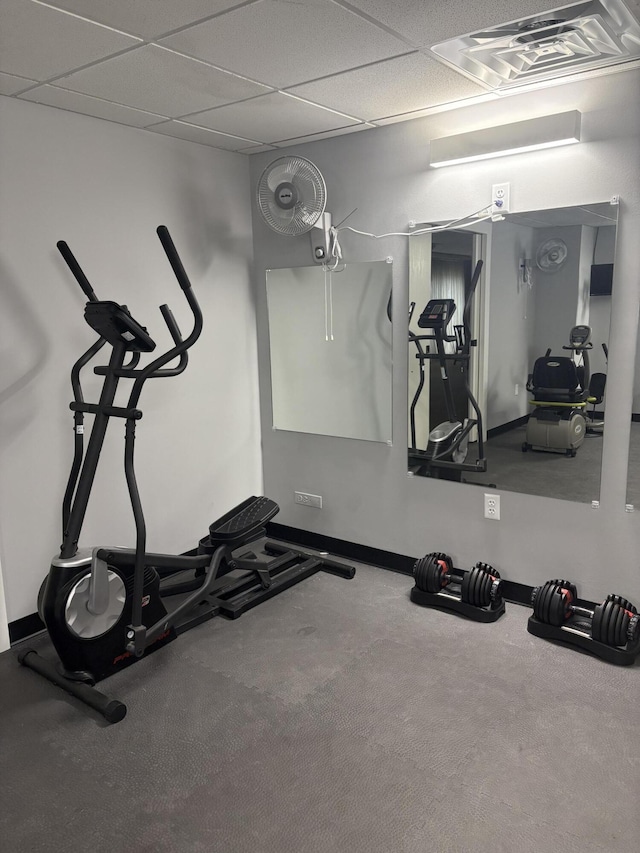 exercise area with visible vents, a paneled ceiling, and baseboards