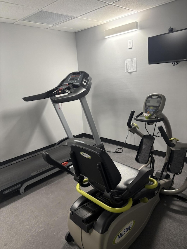 exercise room with baseboards and a drop ceiling