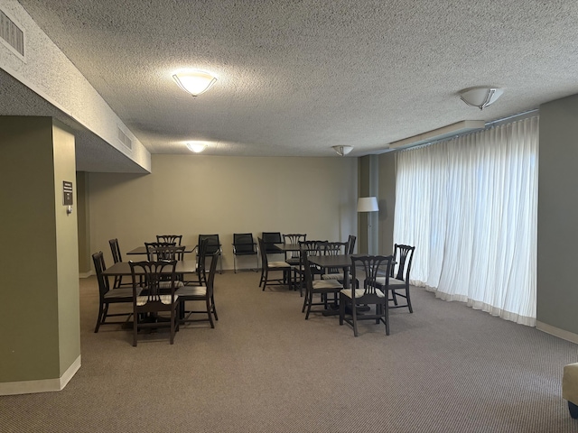 carpeted dining room with visible vents, a textured ceiling, and baseboards