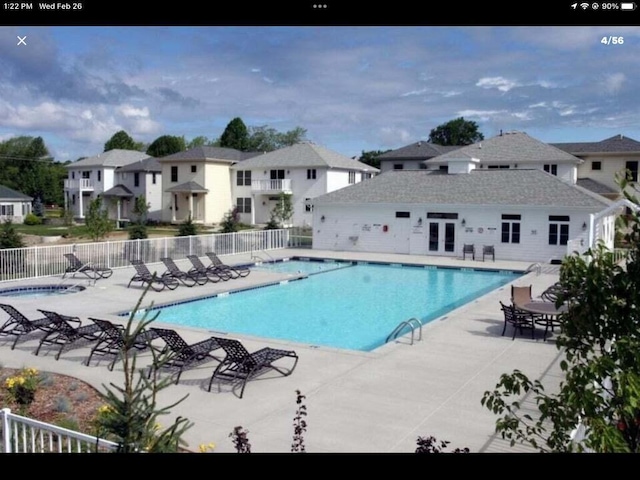 community pool featuring a patio area, a residential view, and fence