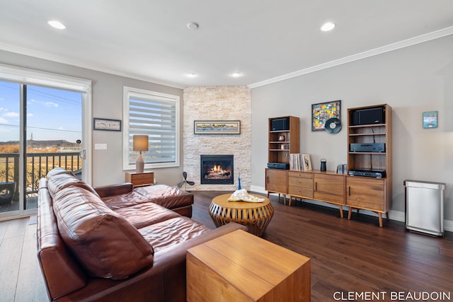 living area with crown molding, a stone fireplace, baseboards, and wood finished floors