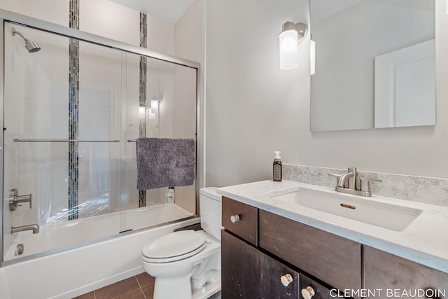 bathroom featuring toilet, tile patterned flooring, enclosed tub / shower combo, and vanity