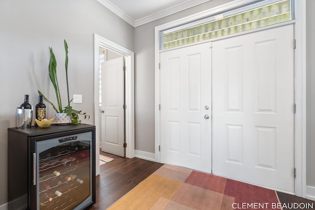 entrance foyer with ornamental molding, wine cooler, wood finished floors, and baseboards