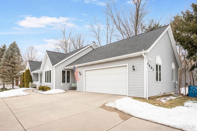 ranch-style house with a garage, concrete driveway, and a shingled roof