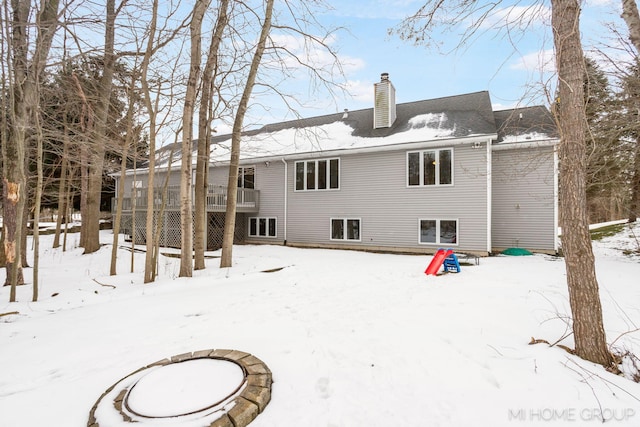 snow covered back of property with a chimney