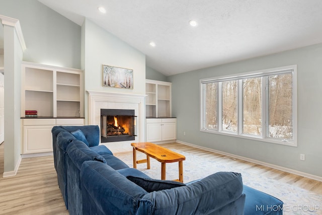 living room with light wood-type flooring, a fireplace, vaulted ceiling, and baseboards