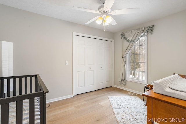 bedroom featuring light wood finished floors, a closet, a ceiling fan, and baseboards