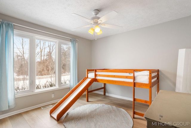 bedroom featuring light wood finished floors, multiple windows, visible vents, and a textured ceiling