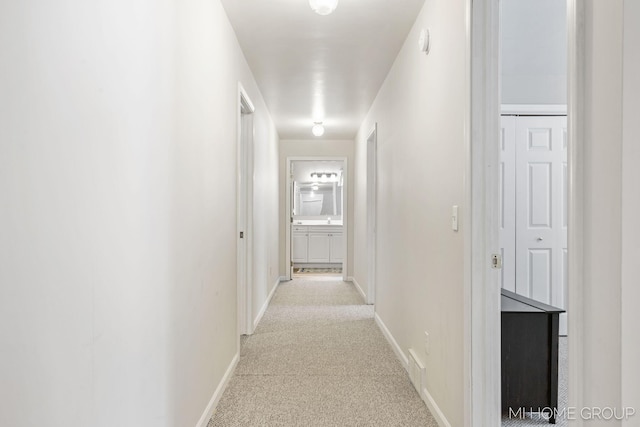 hall with baseboards and light colored carpet