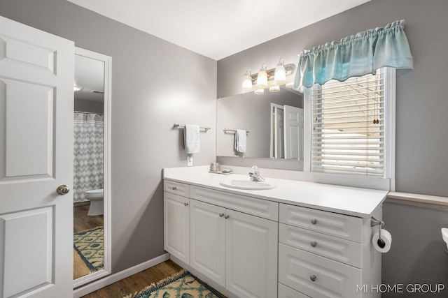 bathroom featuring wood finished floors, vanity, toilet, and baseboards