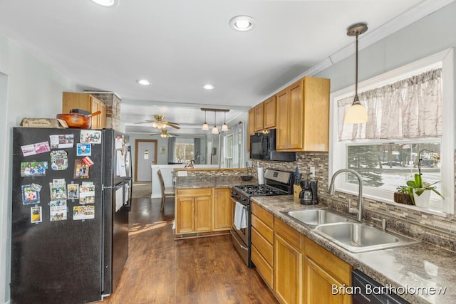 kitchen featuring dark countertops, decorative light fixtures, a sink, and black appliances