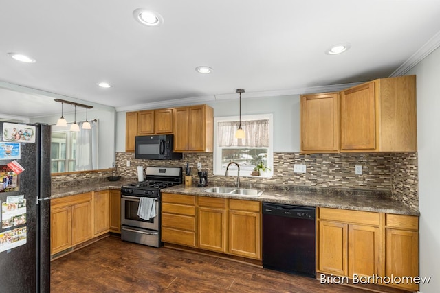 kitchen featuring pendant lighting, dark countertops, ornamental molding, a sink, and black appliances