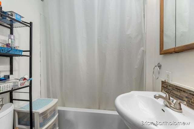 full bathroom featuring tasteful backsplash, a sink, toilet, and shower / bath combo with shower curtain