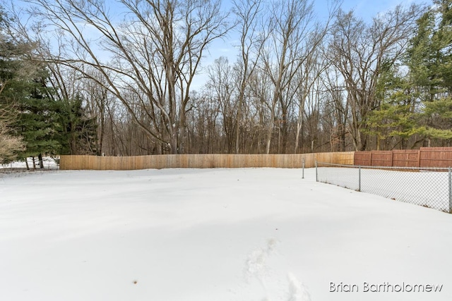 yard layered in snow featuring fence