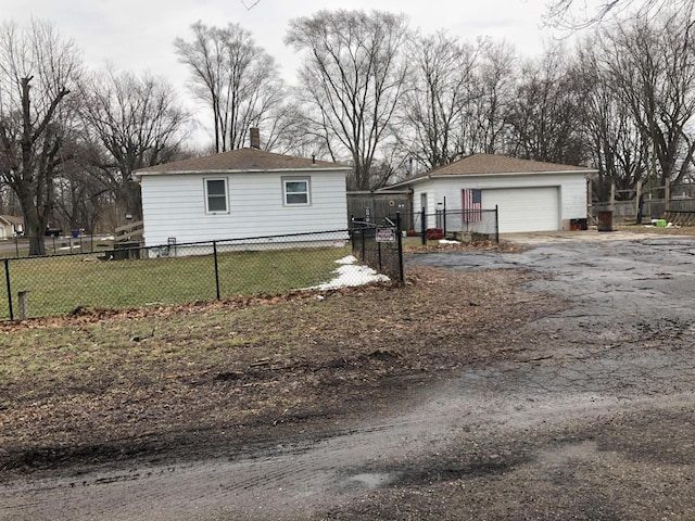 view of home's exterior with a garage, fence, a lawn, and an outdoor structure