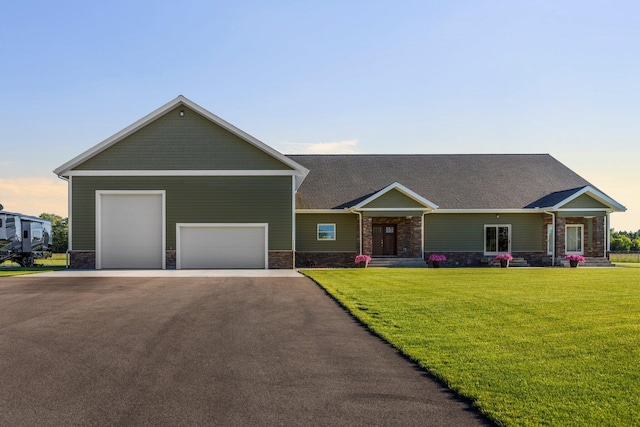 view of front facade with an attached garage, stone siding, aphalt driveway, and a lawn