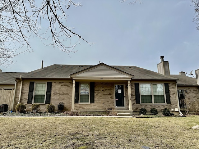 single story home with a chimney, central AC unit, a front lawn, and brick siding