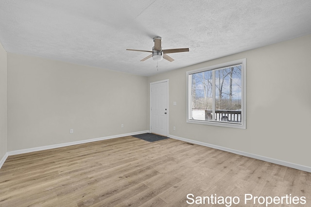 unfurnished room featuring light wood-type flooring, ceiling fan, a textured ceiling, and baseboards