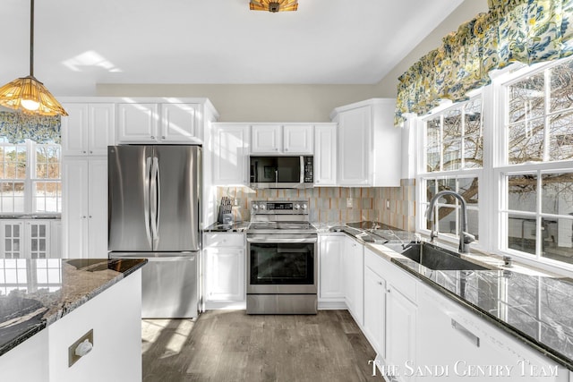 kitchen featuring stainless steel appliances, wood finished floors, a sink, white cabinets, and backsplash