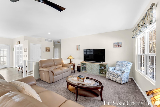 carpeted living area with baseboards, visible vents, and a ceiling fan