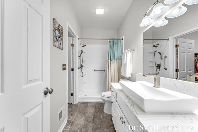 bathroom featuring visible vents, toilet, wood finished floors, curtained shower, and vanity