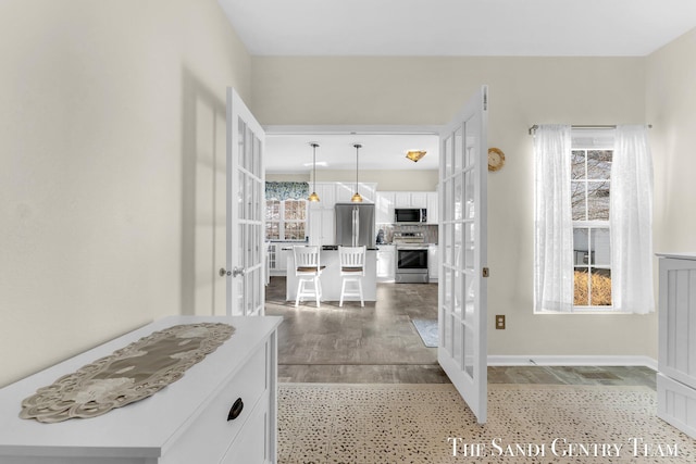 interior space with light wood-style floors, french doors, and a healthy amount of sunlight