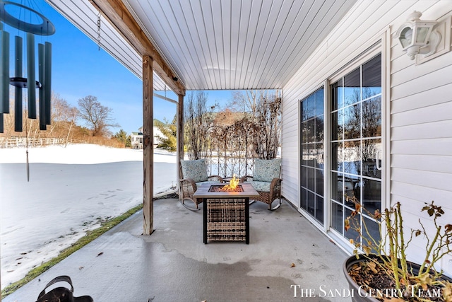 snow covered patio with a fire pit