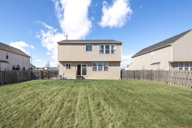 rear view of house with entry steps, a yard, and a fenced backyard