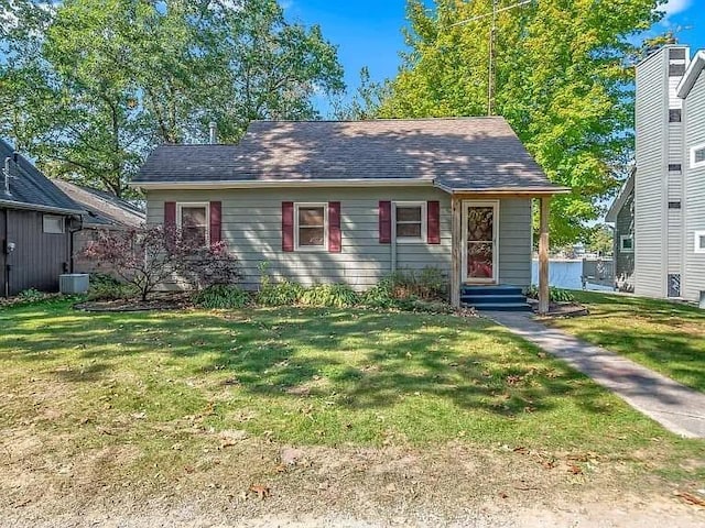 view of front of house featuring entry steps, a front lawn, and a shingled roof