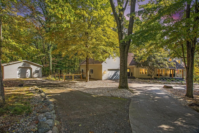 view of front facade with an attached garage, concrete driveway, and an outbuilding