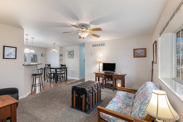 living room featuring a wealth of natural light, baseboards, visible vents, and a ceiling fan