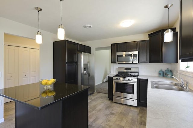 kitchen featuring visible vents, a sink, stainless steel appliances, light wood-style floors, and backsplash