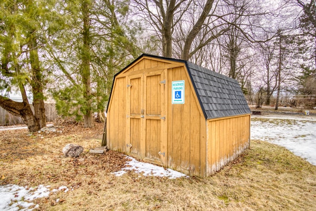 snow covered structure featuring a shed and an outdoor structure