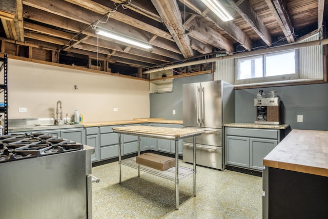 kitchen with light speckled floor, gray cabinets, light countertops, freestanding refrigerator, and a sink