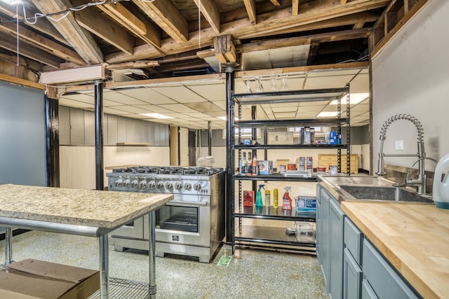 kitchen with butcher block counters, a sink, high end range, and blue cabinets