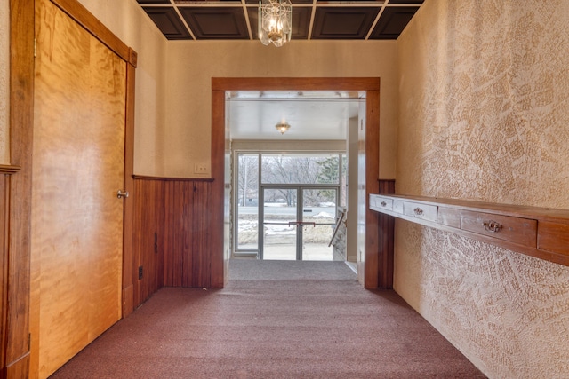 hall with a wainscoted wall, carpet floors, wood walls, and a textured wall