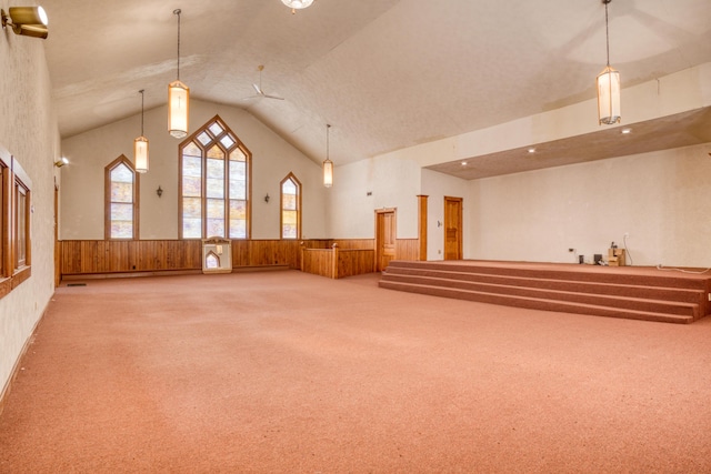 misc room with a wainscoted wall, high vaulted ceiling, carpet, and wooden walls