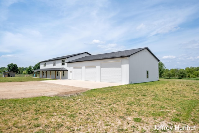 exterior space with driveway, metal roof, a garage, and a front lawn